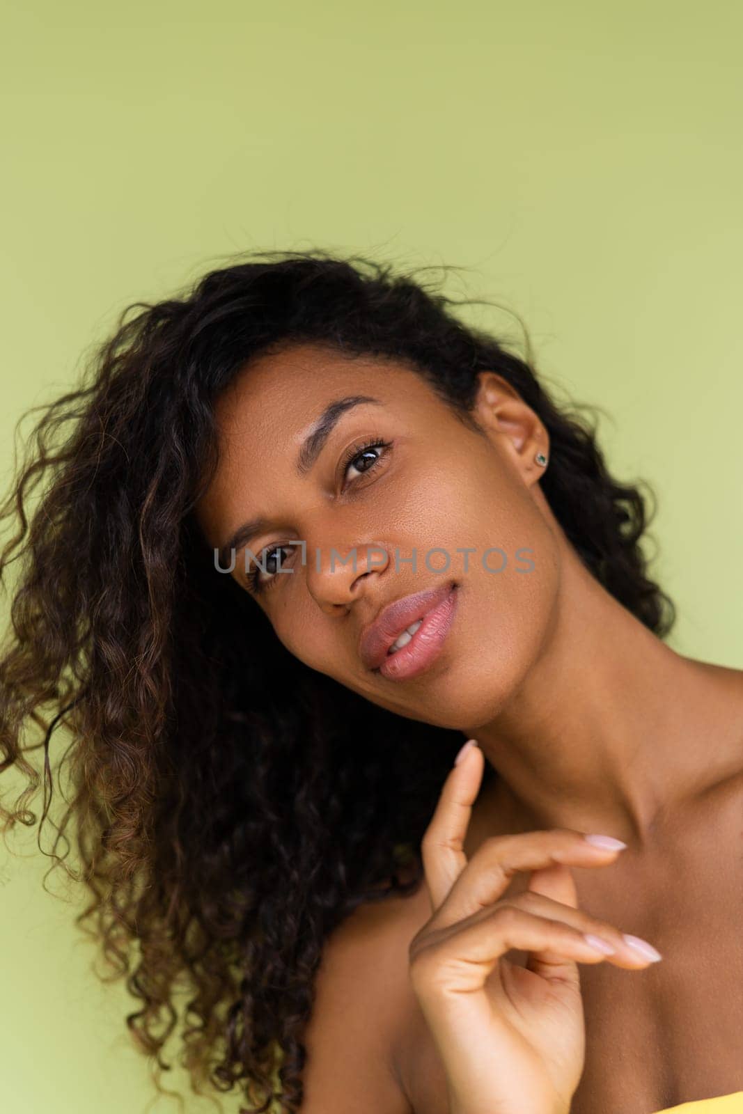 Beauty portrait of young topless african american woman with bare shoulders on green background with perfect skin and natural makeup