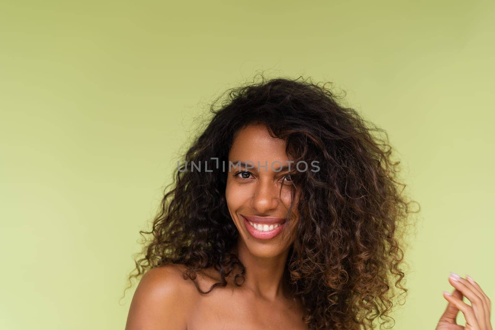 Beauty portrait of young topless african american woman with bare shoulders on green background with perfect skin and natural makeup by kroshka_nastya