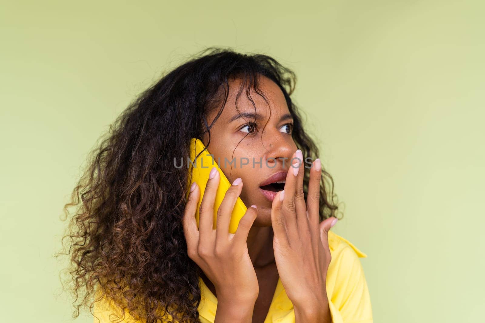 Beautiful african american woman in casual shirt on green background talk on mobile phone shocked confused by kroshka_nastya