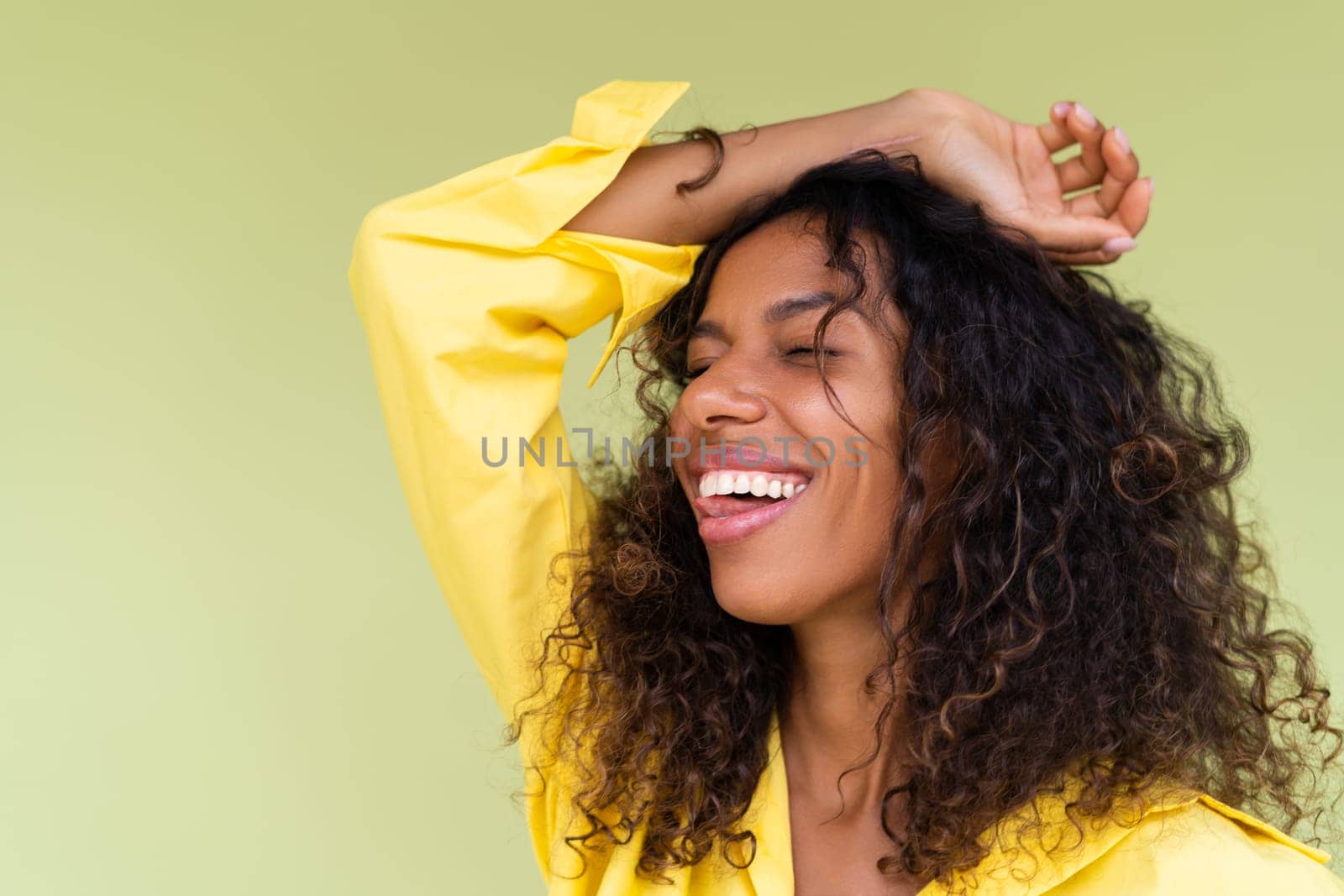 Beautiful african american woman in casual shirt on green background positive smiling laughing enjoying execited