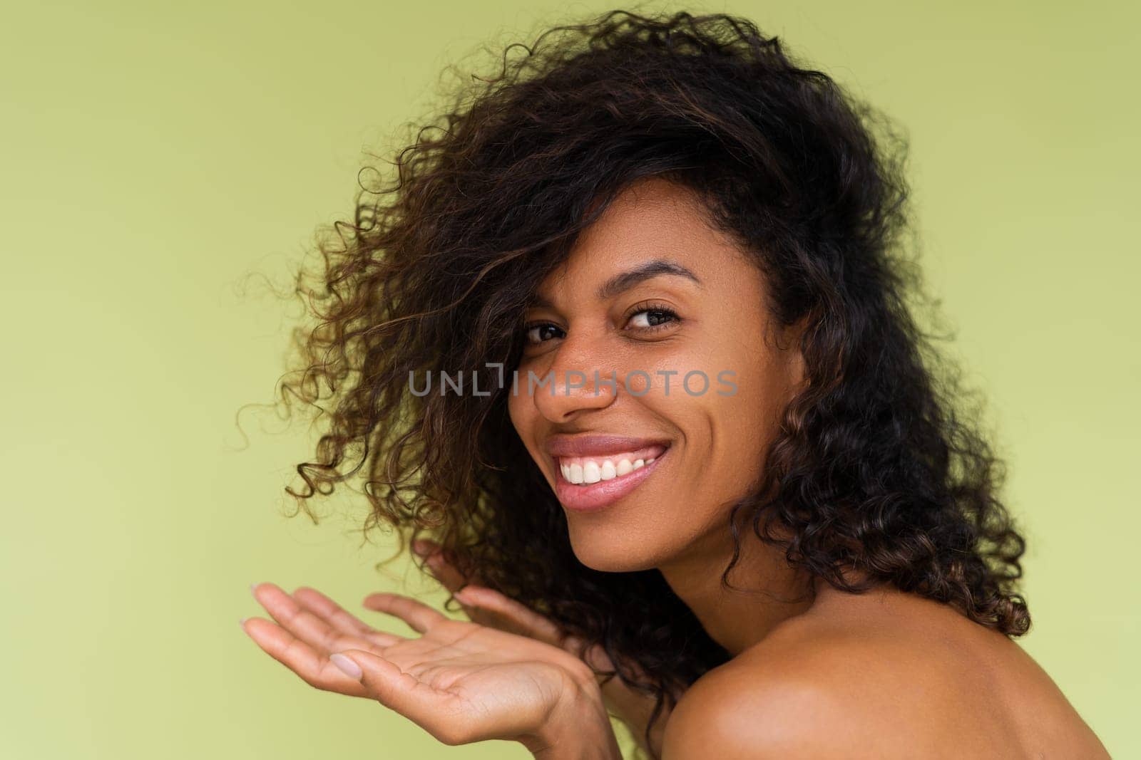 Beauty portrait of young topless african american woman with bare shoulders on green background with perfect skin and natural makeup by kroshka_nastya