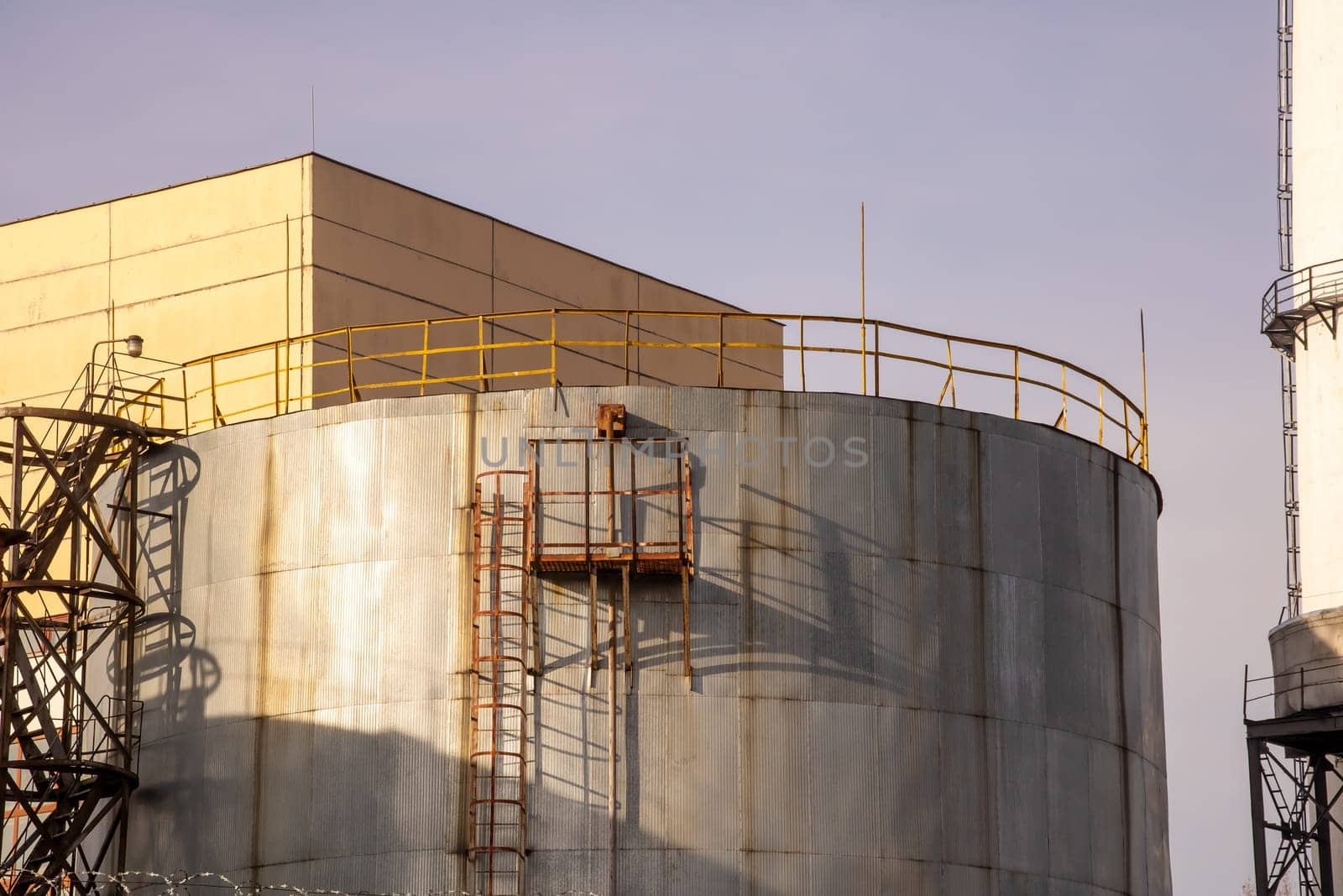 Large plant pipes and ladders on blue sky background close up
