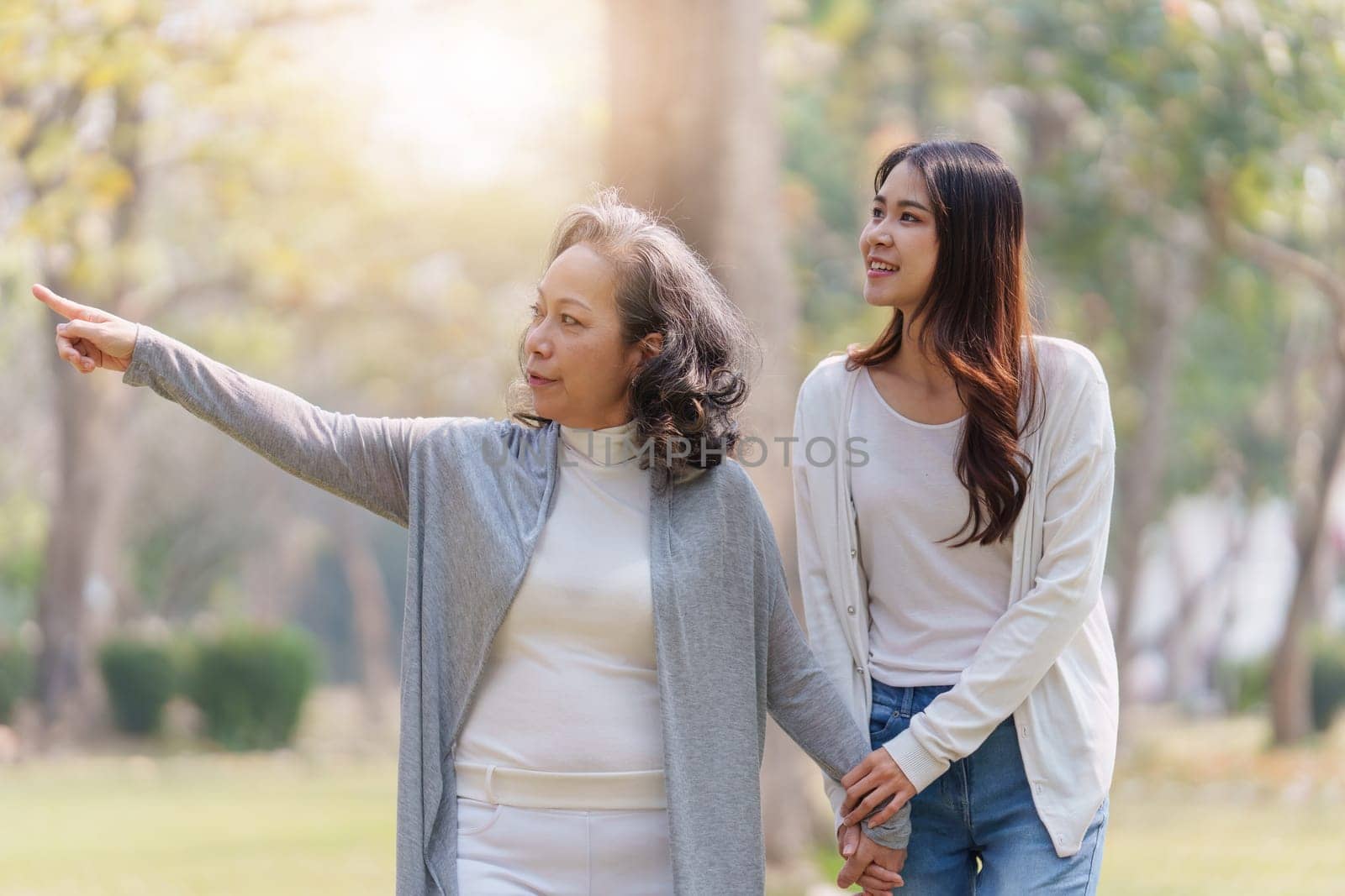 Adult daughter holding her elderly mother hand with love and walk together by itchaznong