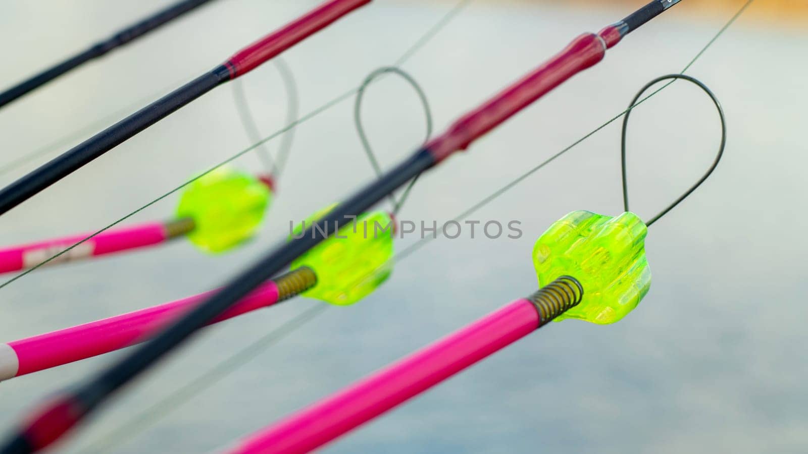 The bite alarm hangs on a fishing rod against the background of water. Fishing rod while fishing on the lake, river. Fishing tackle. Carp rod on a stand with a bite alarm on the line