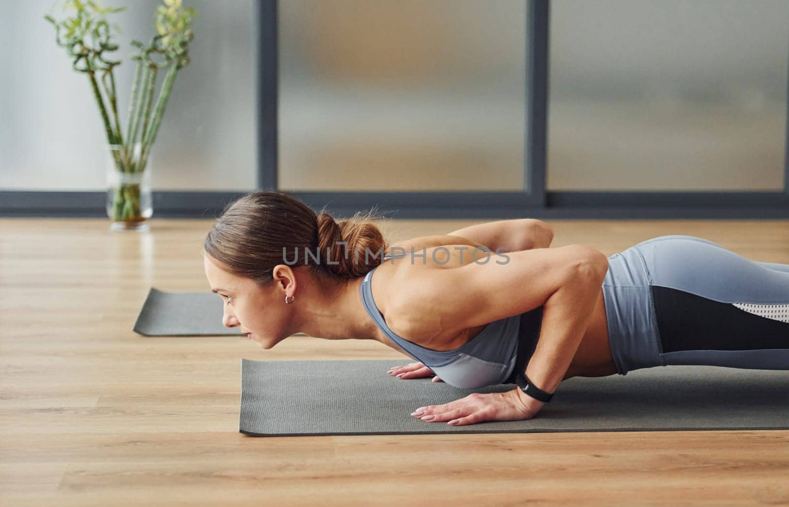 Doing push ups. Young woman in sportive wear and with slim body have fitness yoga day indoors by Standret