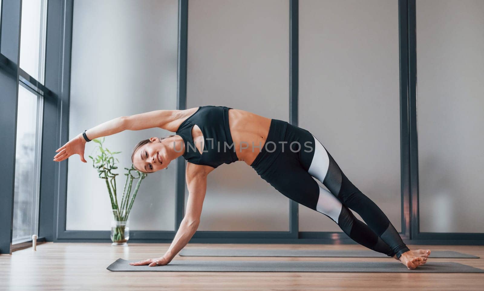 Concentrated on exercise. Young woman in sportive wear and with slim body have fitness yoga day indoors.