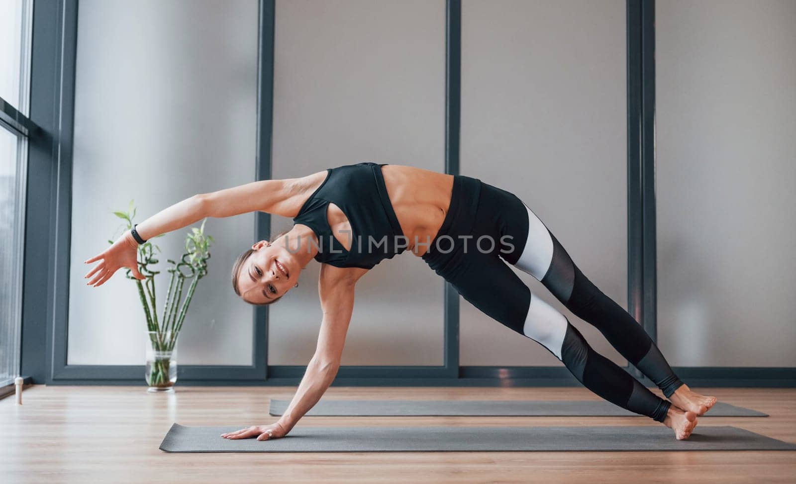 Concentrated on exercise. Young woman in sportive wear and with slim body have fitness yoga day indoors by Standret