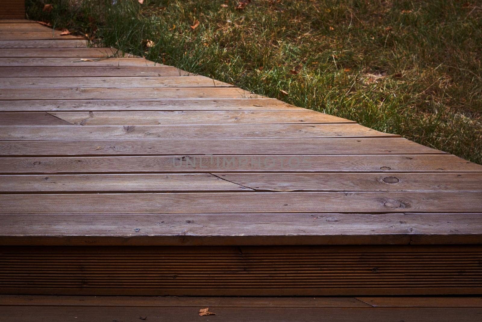 The wooden flooring of the stage next to the green lawn. Decking. Paths in the country. Construction and repair.