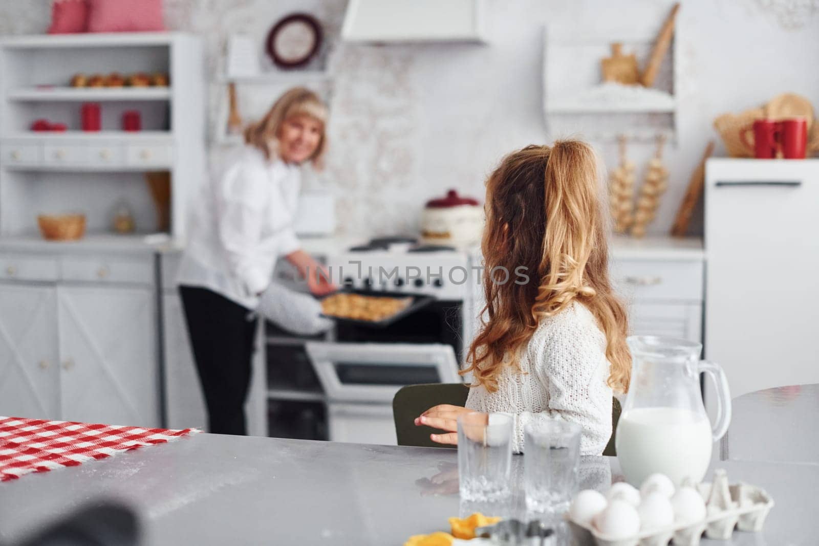 Finished product. Senior grandmother with her little granddaughter cooks sweets for Christmas on the kitchen.