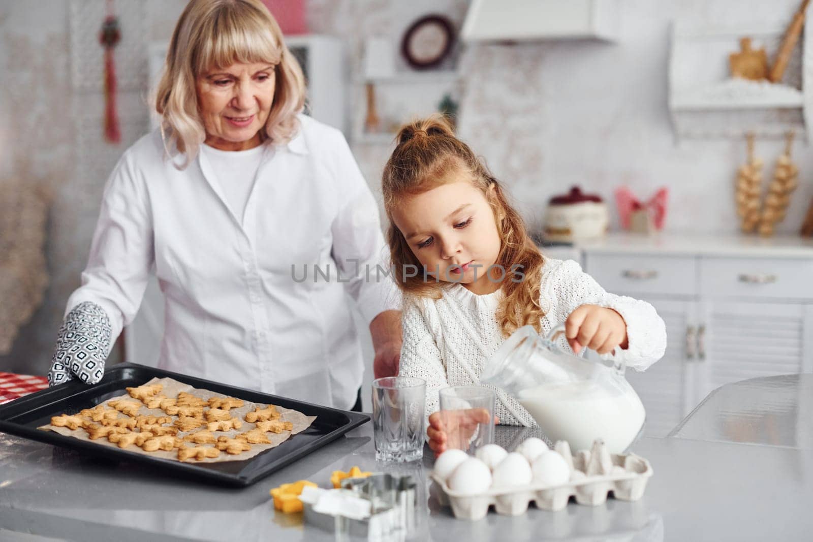 Finished product. Senior grandmother with her little granddaughter cooks sweets for Christmas on the kitchen.