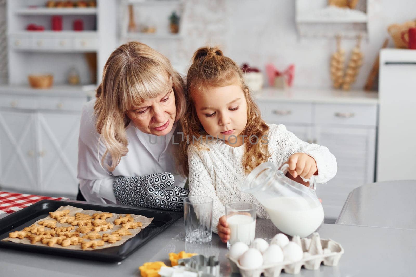 Finished product. Senior grandmother with her little granddaughter cooks sweets for Christmas on the kitchen.