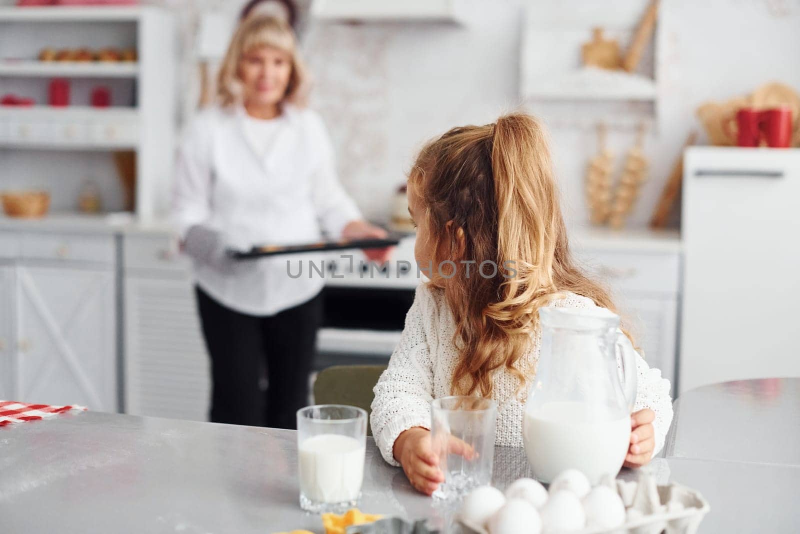 Finished product. Senior grandmother with her little granddaughter cooks sweets for Christmas on the kitchen.