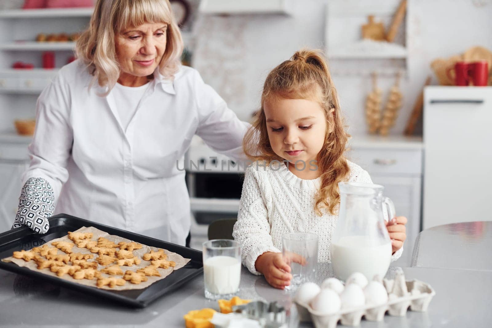 Finished product. Senior grandmother with her little granddaughter cooks sweets for Christmas on the kitchen.