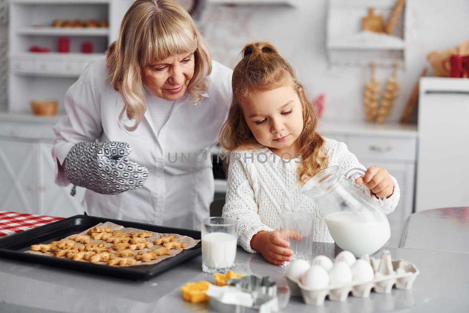 Finished product. Senior grandmother with her little granddaughter cooks sweets for Christmas on the kitchen.
