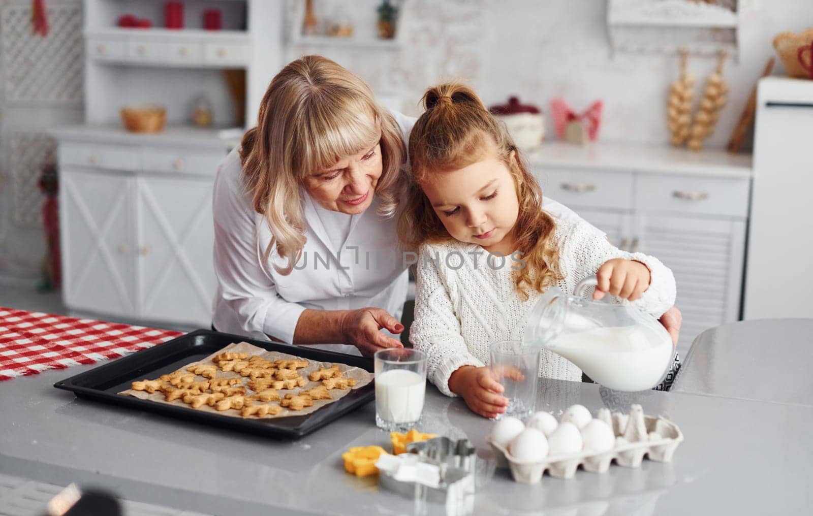 Finished product. Senior grandmother with her little granddaughter cooks sweets for Christmas on the kitchen.