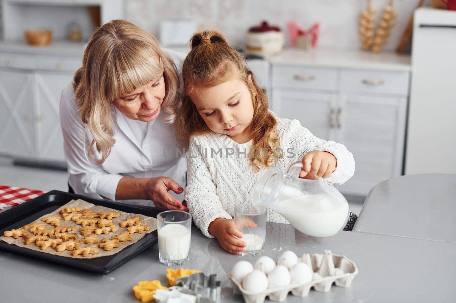 Finished product. Senior grandmother with her little granddaughter cooks sweets for Christmas on the kitchen.
