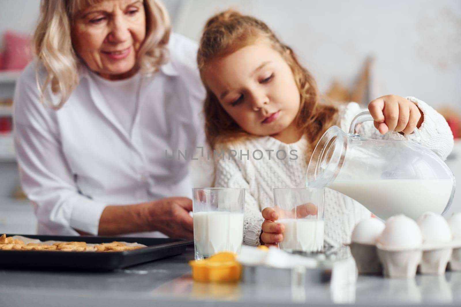 Finished product. Senior grandmother with her little granddaughter cooks sweets for Christmas on the kitchen.