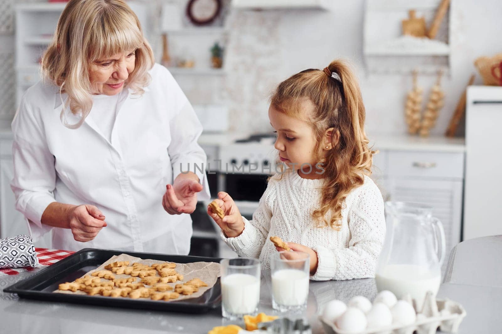Finished product. Senior grandmother with her little granddaughter cooks sweets for Christmas on the kitchen.