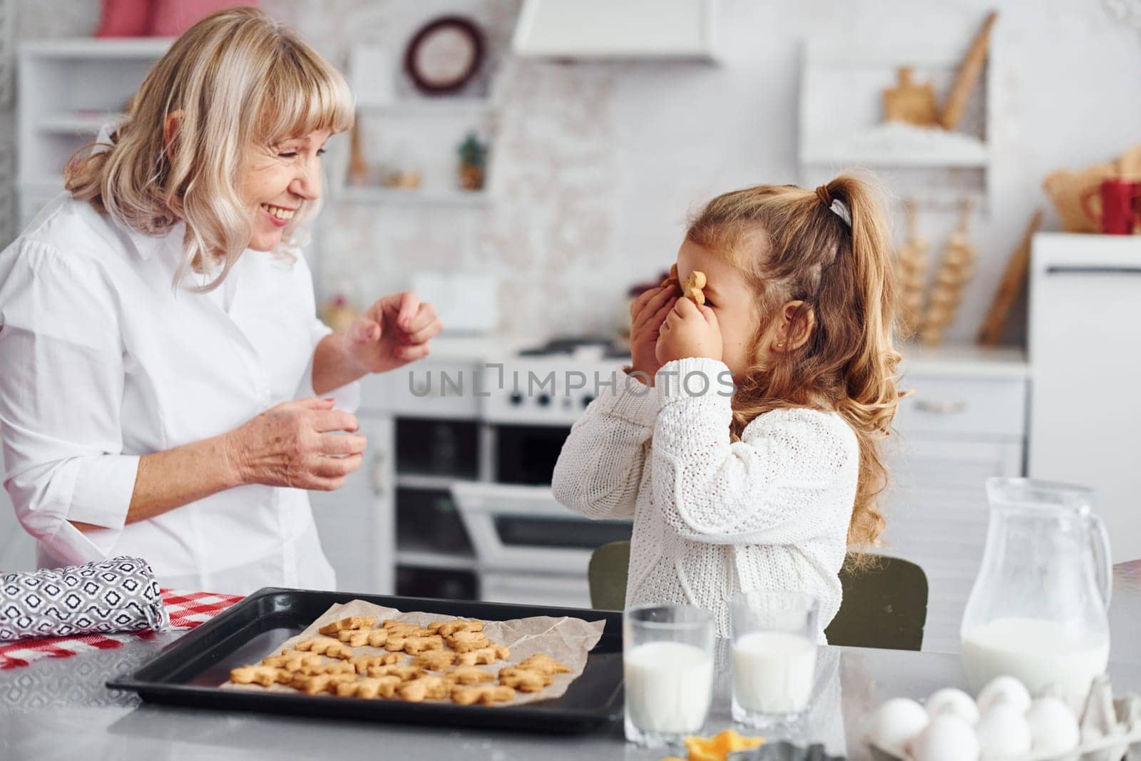 Finished product. Senior grandmother with her little granddaughter cooks sweets for Christmas on the kitchen.