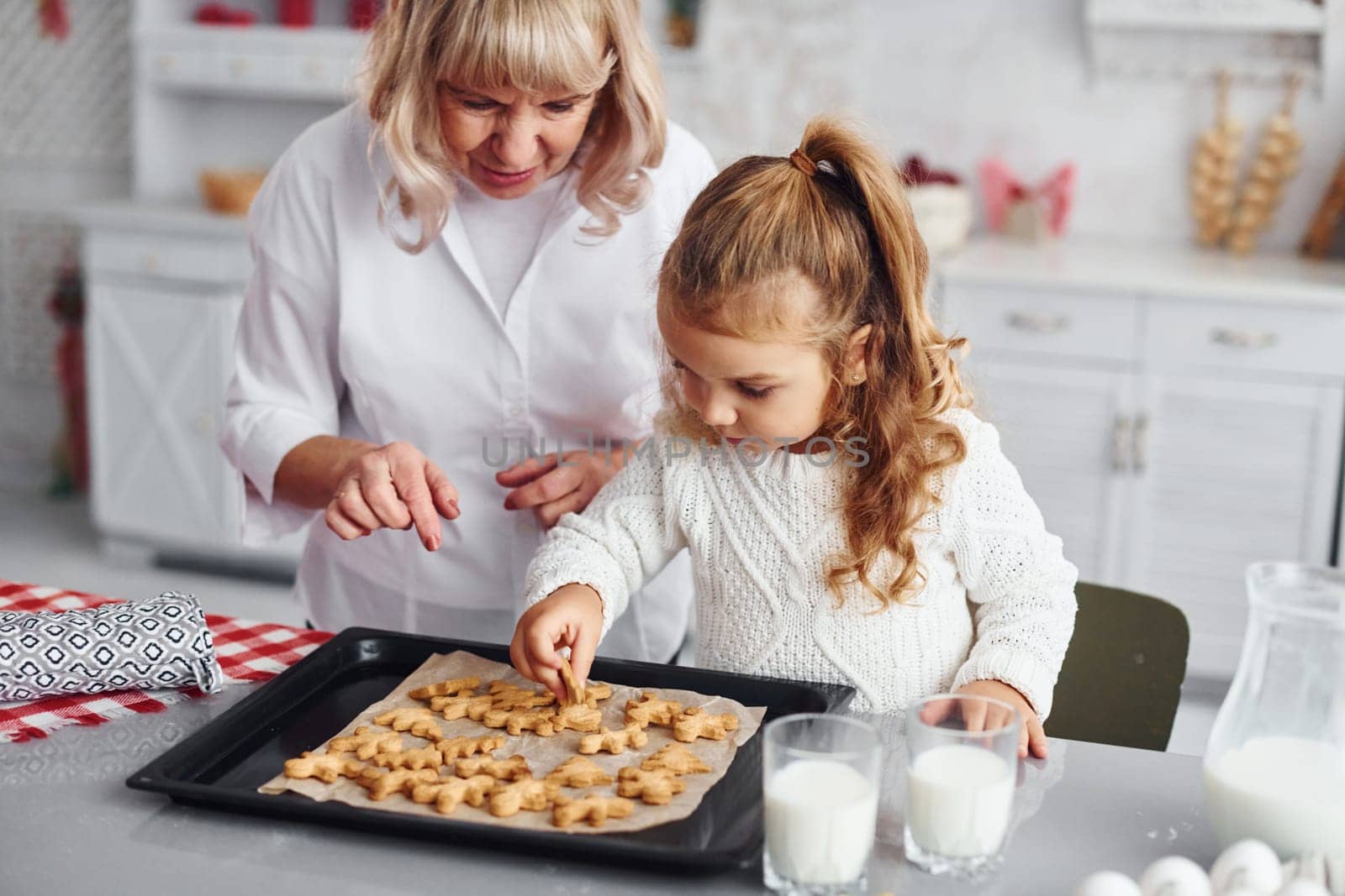Finished product. Senior grandmother with her little granddaughter cooks sweets for Christmas on the kitchen.