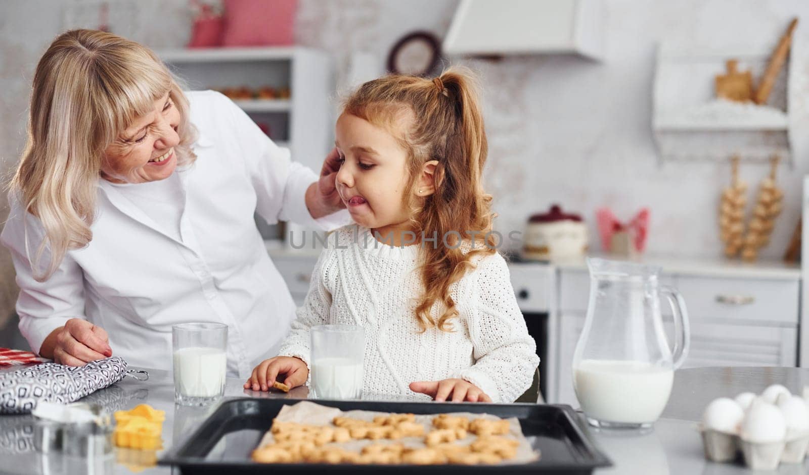 Finished product. Senior grandmother with her little granddaughter cooks sweets for Christmas on the kitchen.