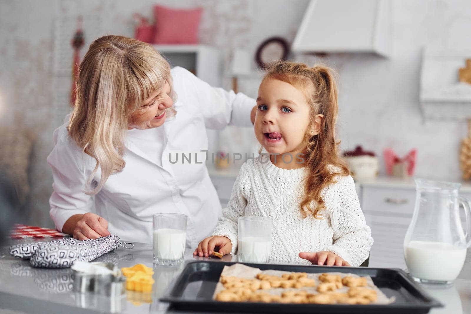 Ready to eat. Senior grandmother with her little granddaughter cooks sweets for Christmas on the kitchen.