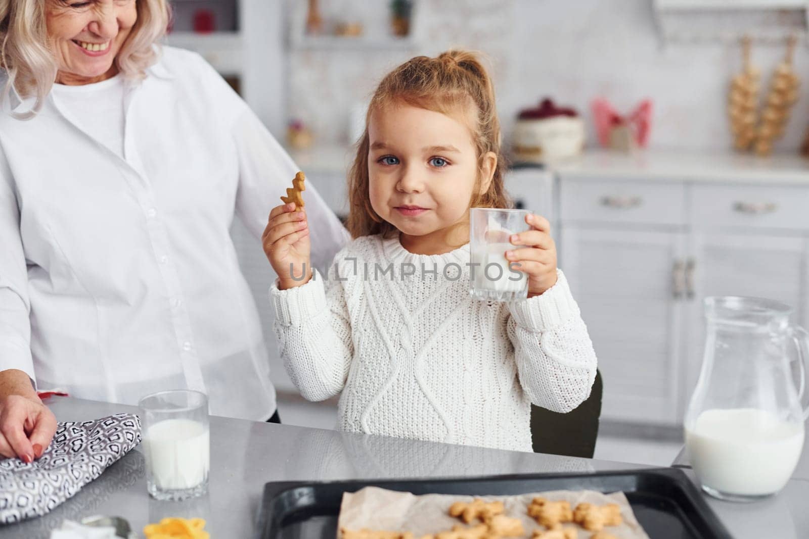 Ready to eat. Senior grandmother with her little granddaughter cooks sweets for Christmas on the kitchen.