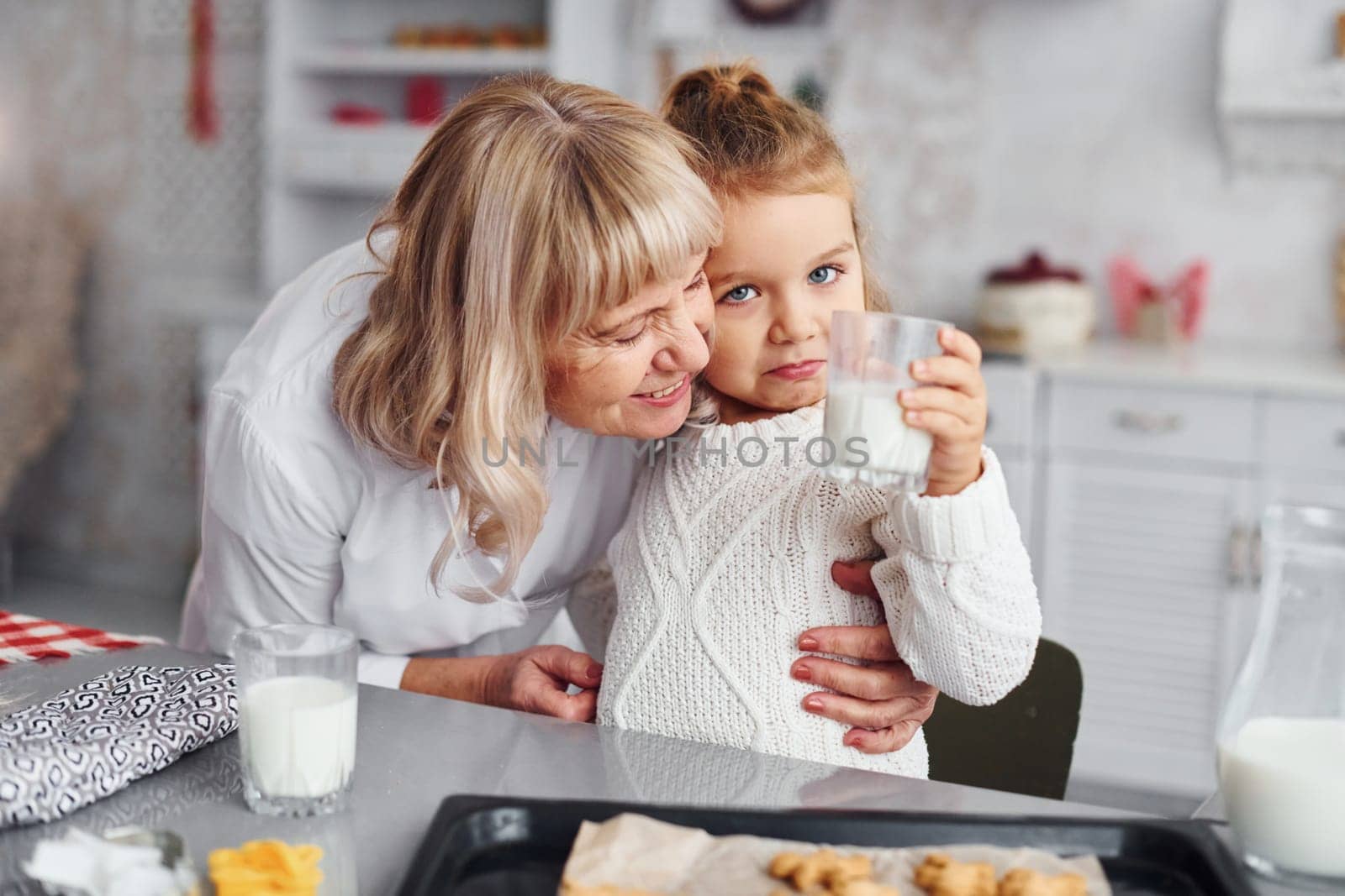 Ready to eat. Senior grandmother with her little granddaughter cooks sweets for Christmas on the kitchen.