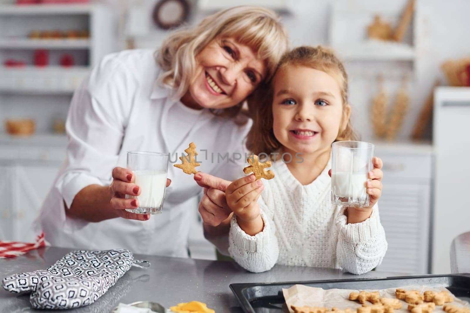 Ready to eat. Senior grandmother with her little granddaughter cooks sweets for Christmas on the kitchen.