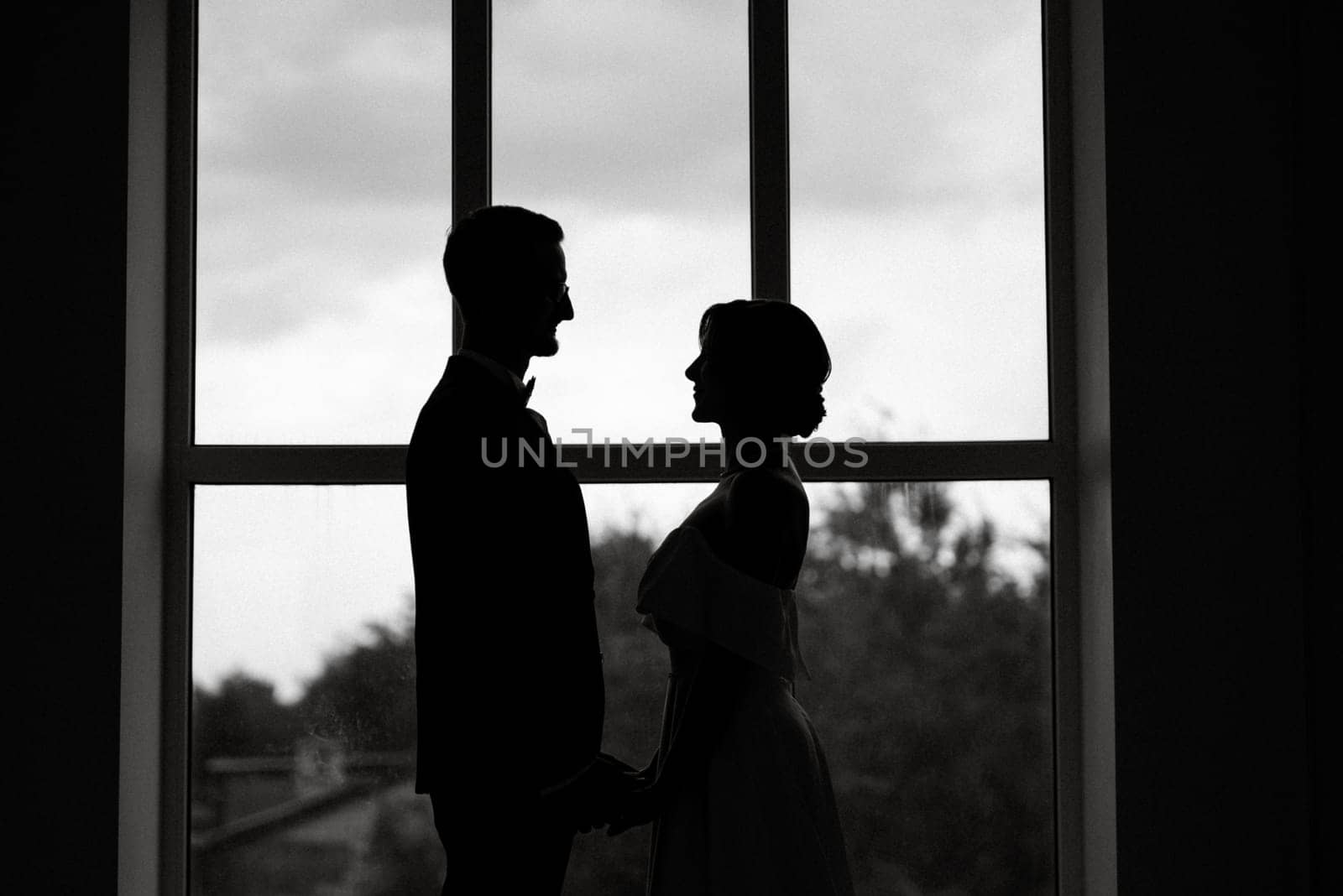 groom in a black suit tie and the bride in a bright studio by Andreua