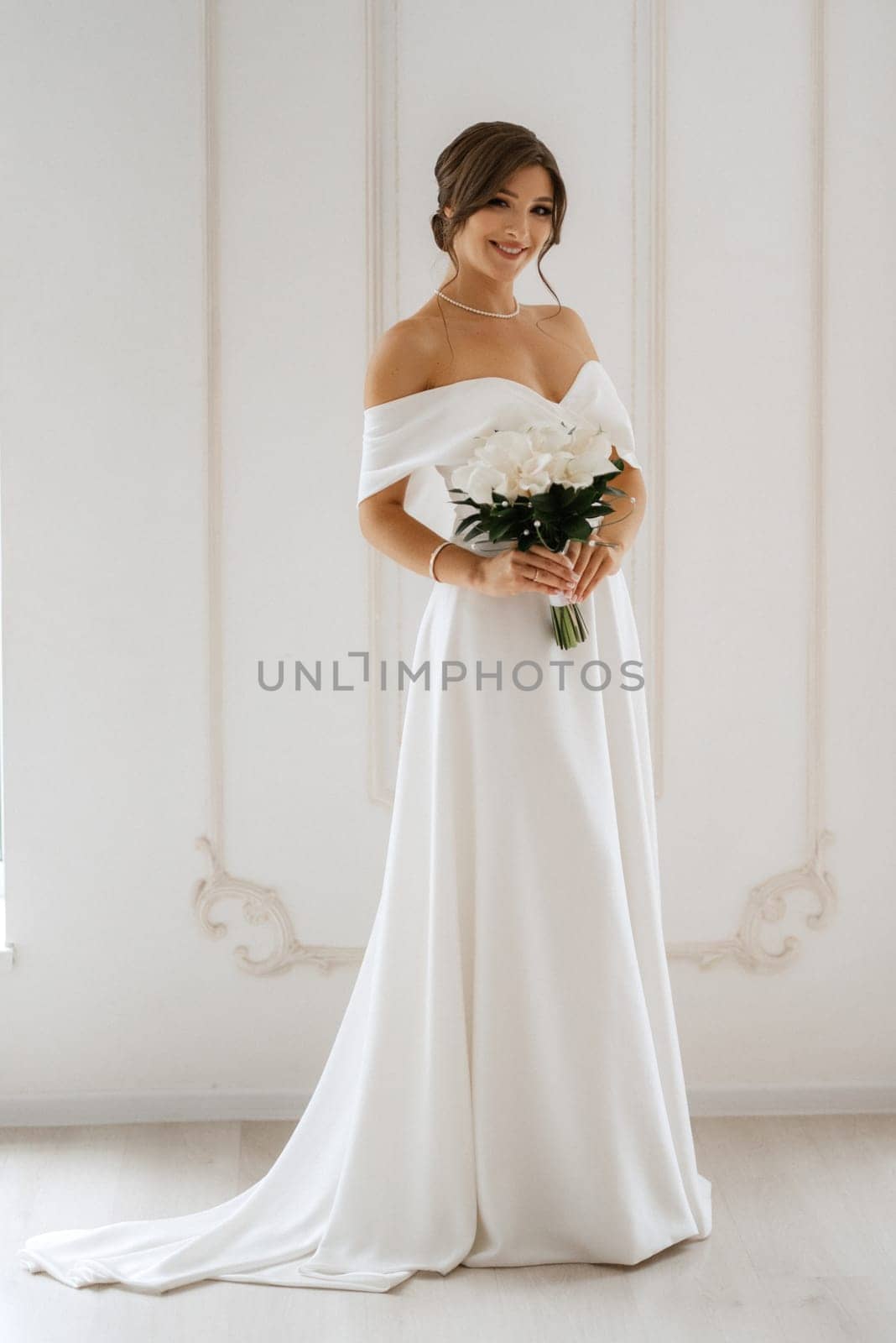 brunette bride in a tight wedding dress in a bright studio with a bouquet