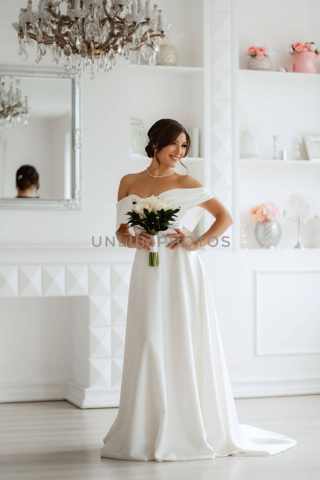 brunette bride in a tight wedding dress in a bright studio with a bouquet