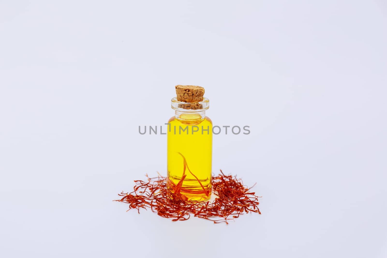 Oil extract from saffron stamens on a white background. Dry threads of saffron.