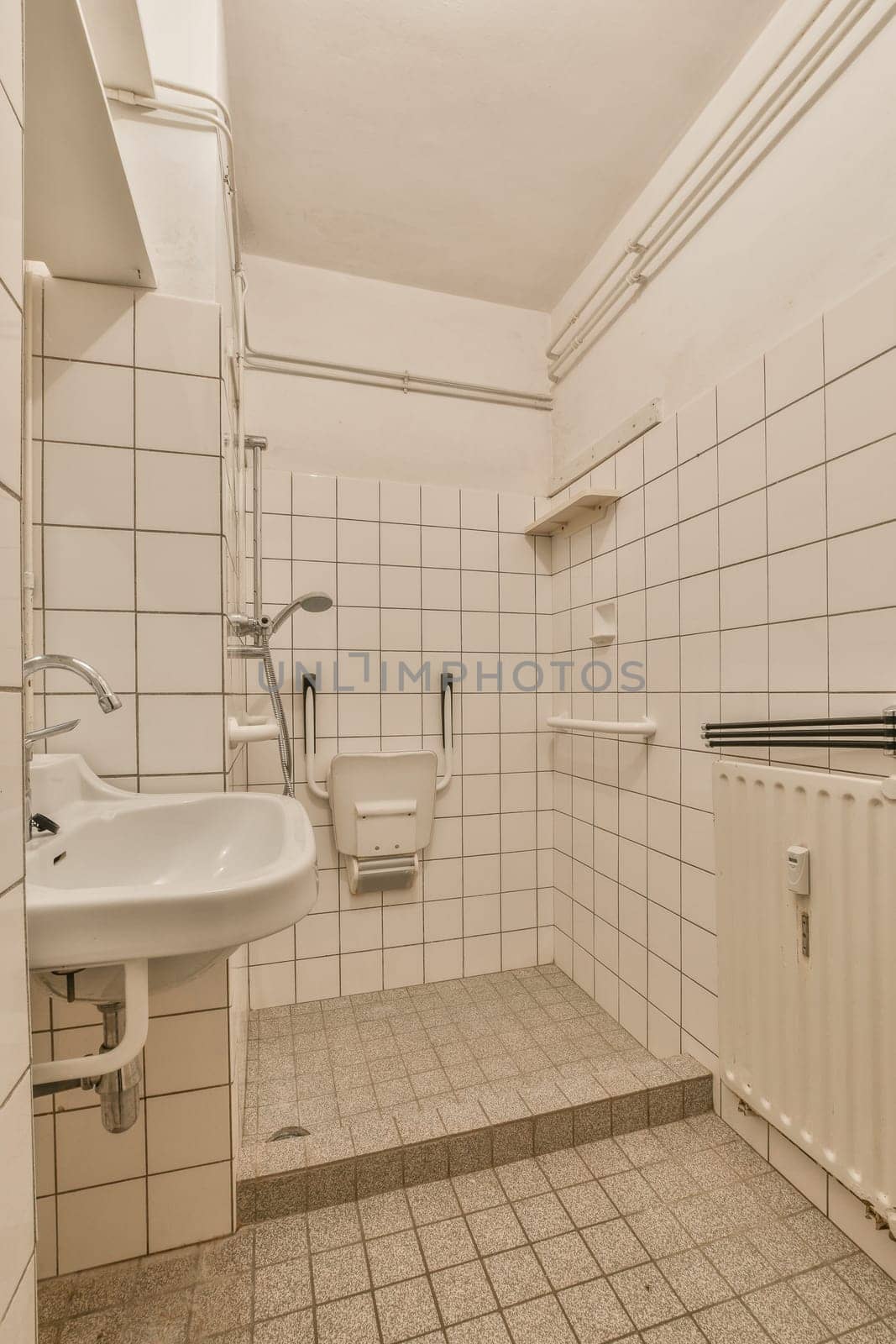 a bathroom with white tiles on the walls and floor, there is a small sink in the corner next to the toilet