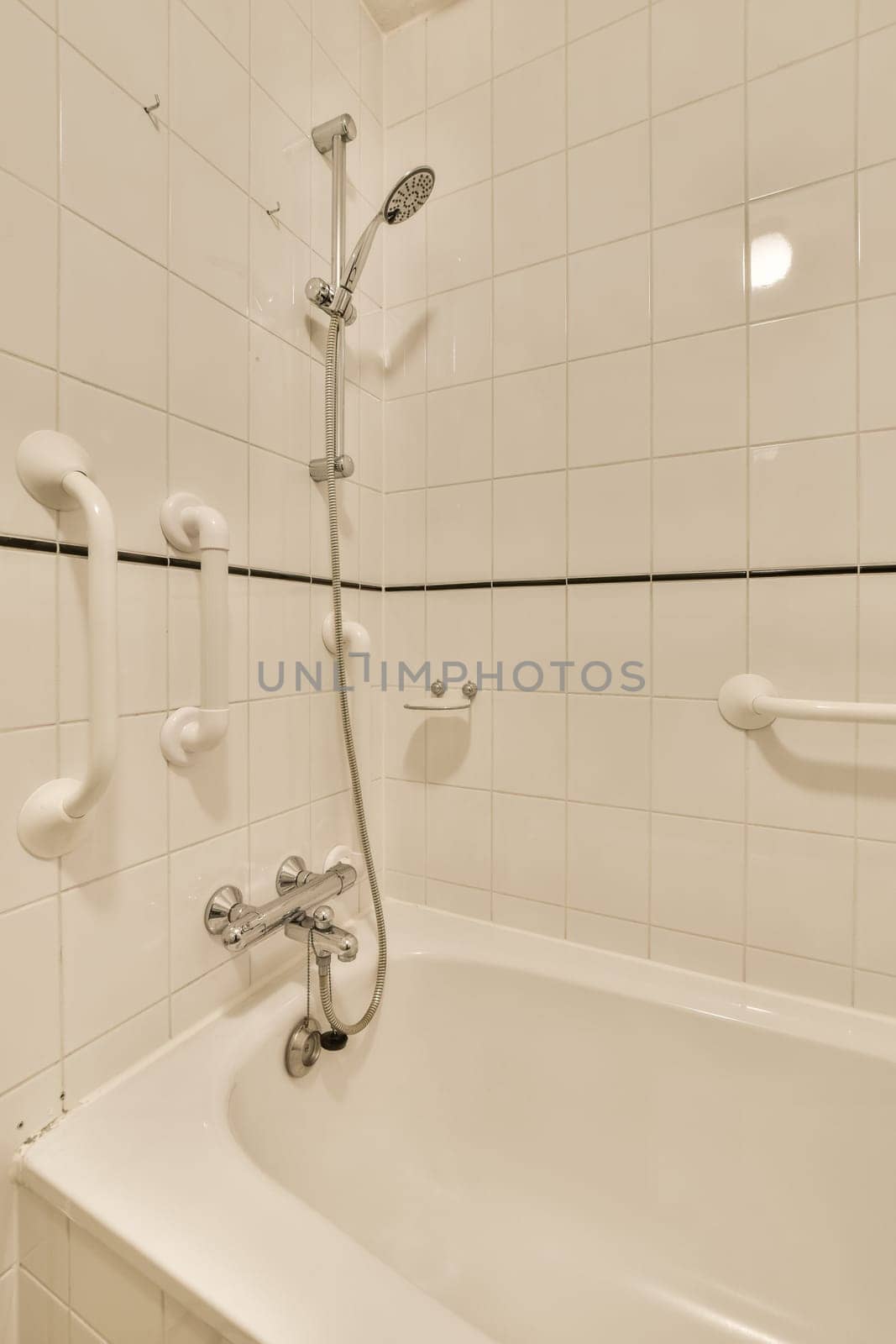 a bathroom with white tiles and black lines on the wall, as seen from the corner of the bathtub