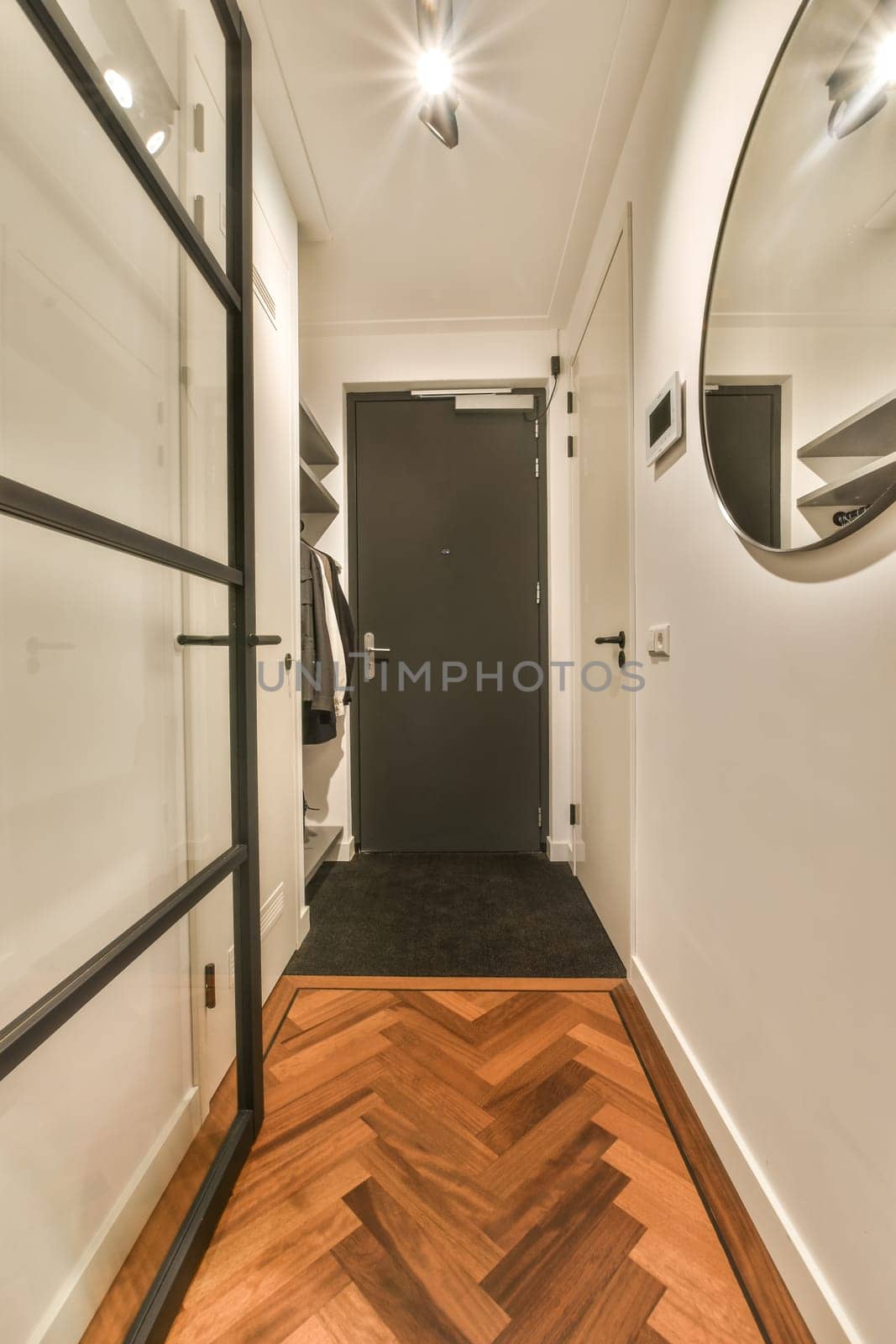 a hallway with a black door and wood flooring by casamedia
