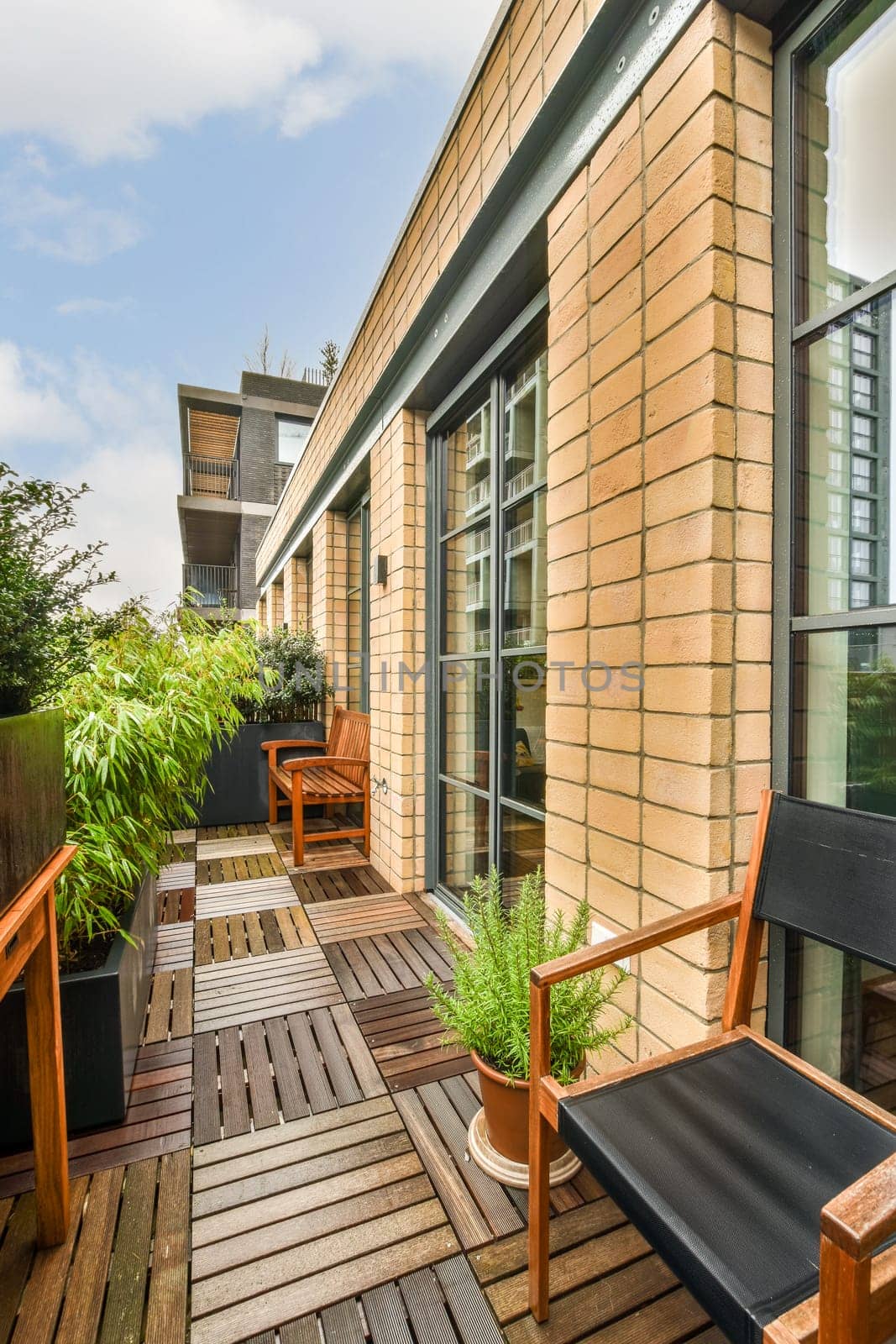 a balcony with wooden deck furniture and a brick building by casamedia