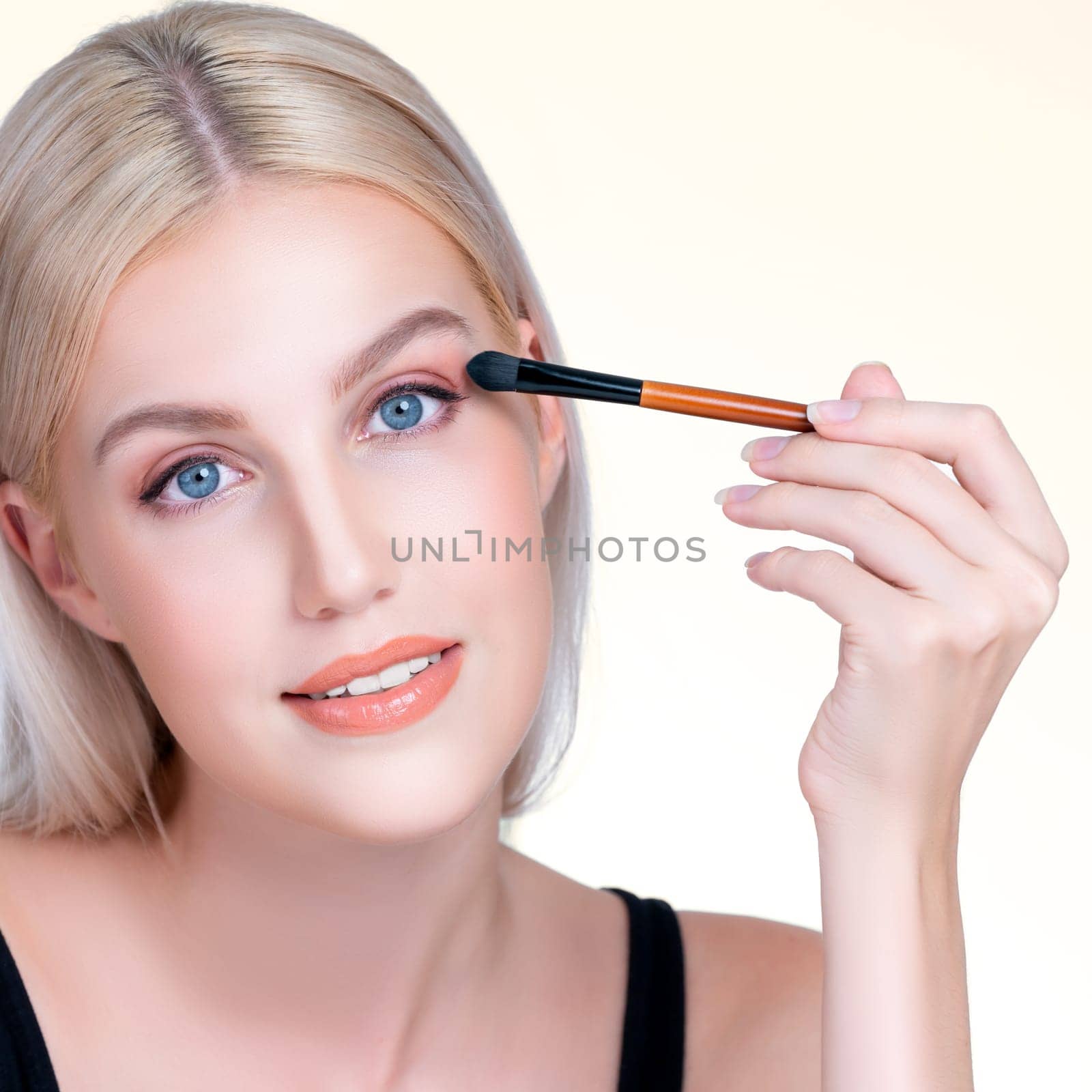 Closeup beautiful personable girl with flawless applying eye shadow makeup. by biancoblue