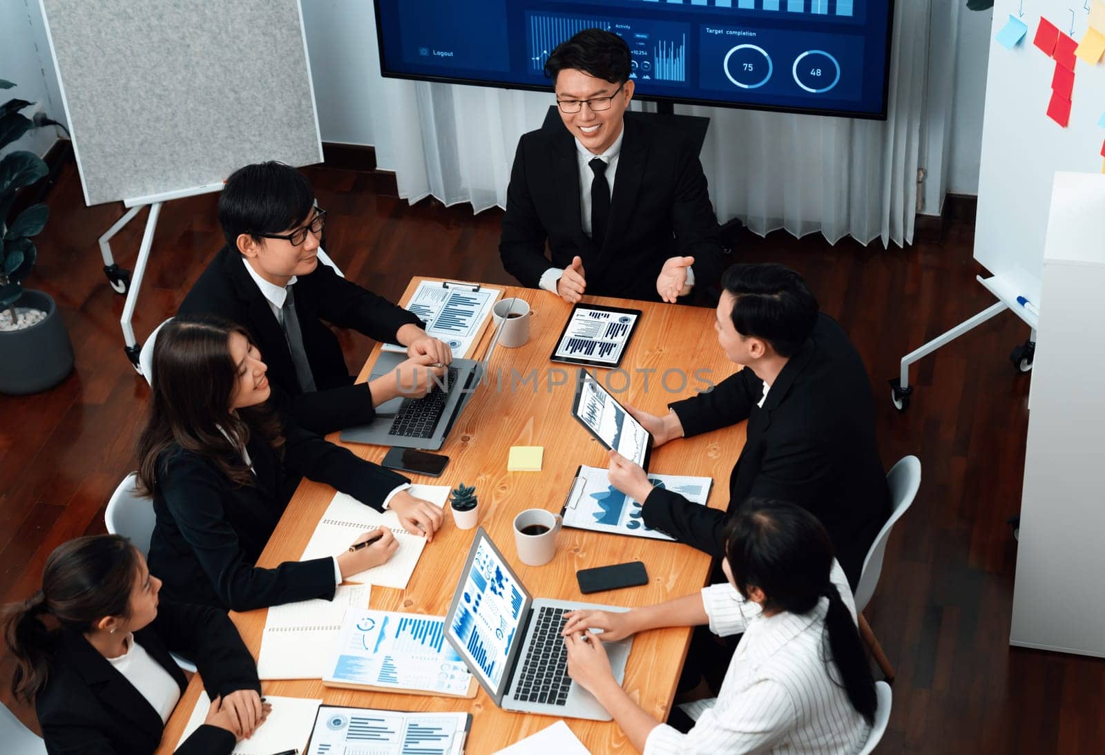 Top-view business team of financial data analysis meeting with business intelligence, report paper and dashboard on laptop for marketing strategy. Business people working together in office of harmony