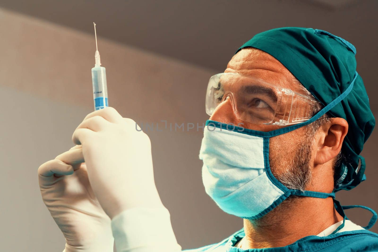 Surgeon fill syringe from medical vial for surgical procedure at sterile operation room. Doctor in full protective wear for surgery prepare anesthesia injection for his patient