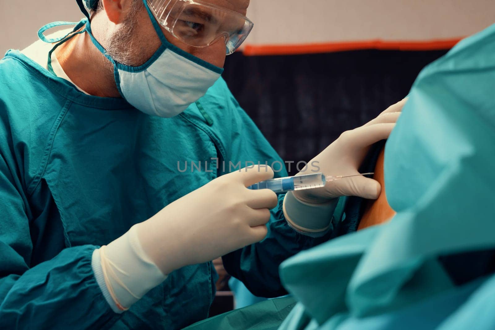 Surgeon inject anesthesia with syringe into the patient before perform surgery in sterile operation room with modern surgical equipments. Medical surgery perform by professional and confident surgeon.