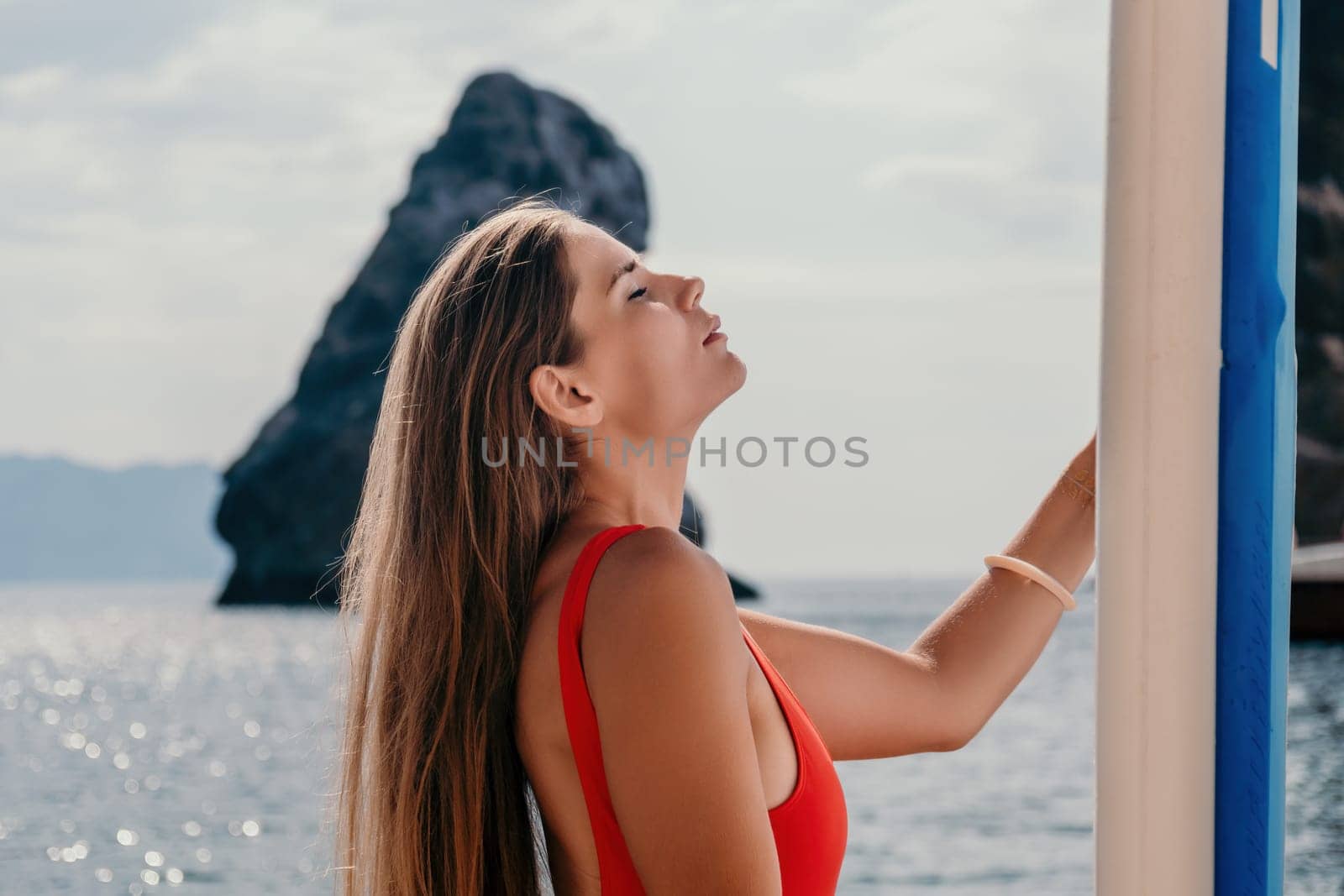 Woman sea sup. Close up portrait of happy young caucasian woman with long hair looking at camera and smiling. Cute woman portrait in bikini posing on sup board in the sea by panophotograph