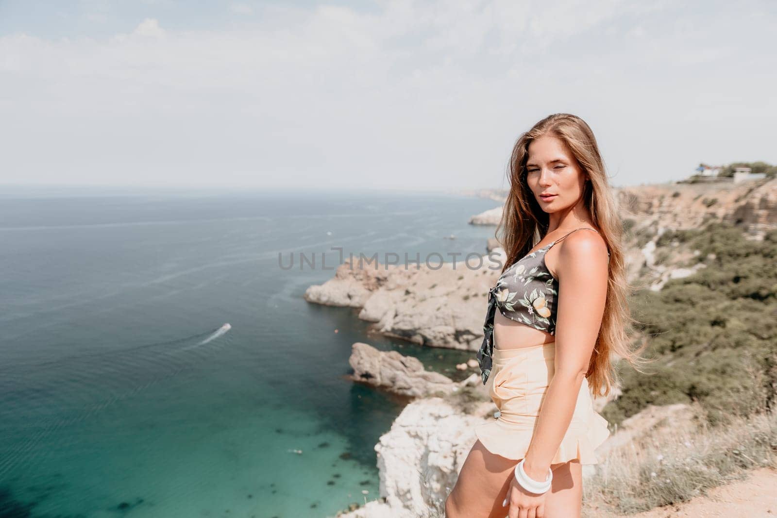 Woman travel sea. Happy tourist enjoy taking picture outdoors for memories. Woman traveler looks at the edge of the cliff on the sea bay of mountains, sharing travel adventure journey by panophotograph