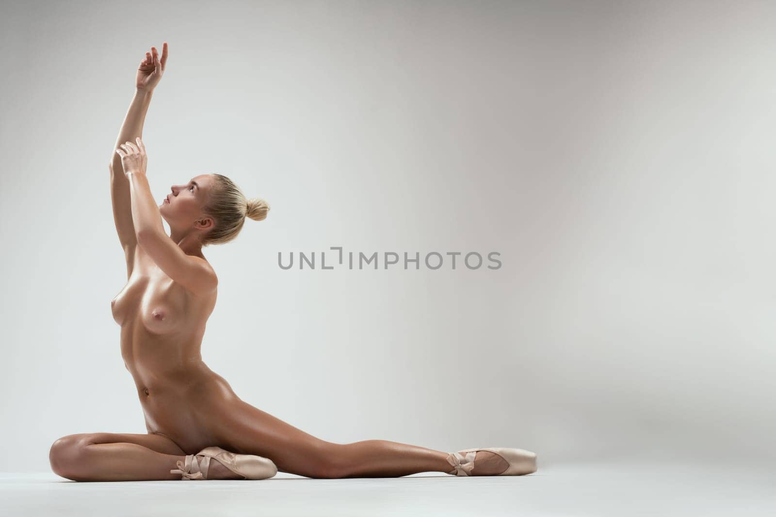 Full body side view of nude ballet model sitting on floor in studio