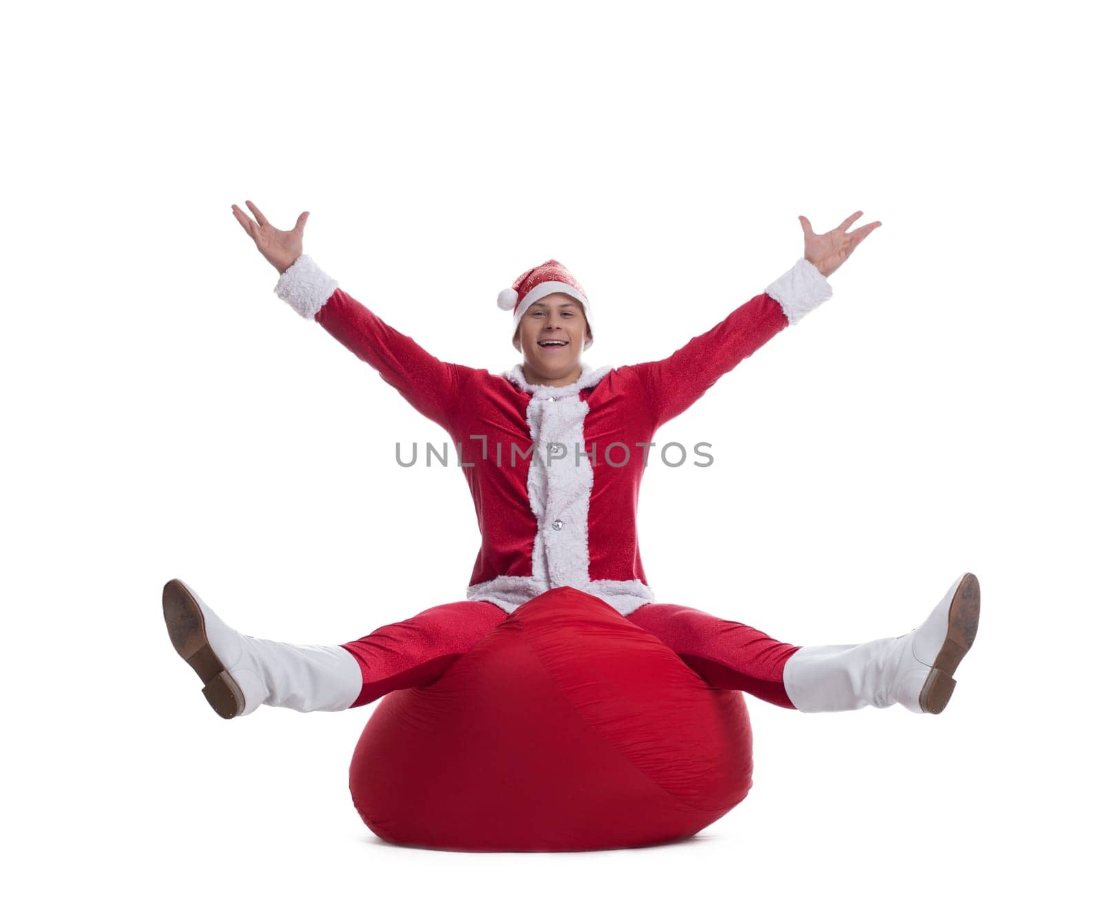 Full length portrait of happy young Santa sitting on bag. Isolated on white