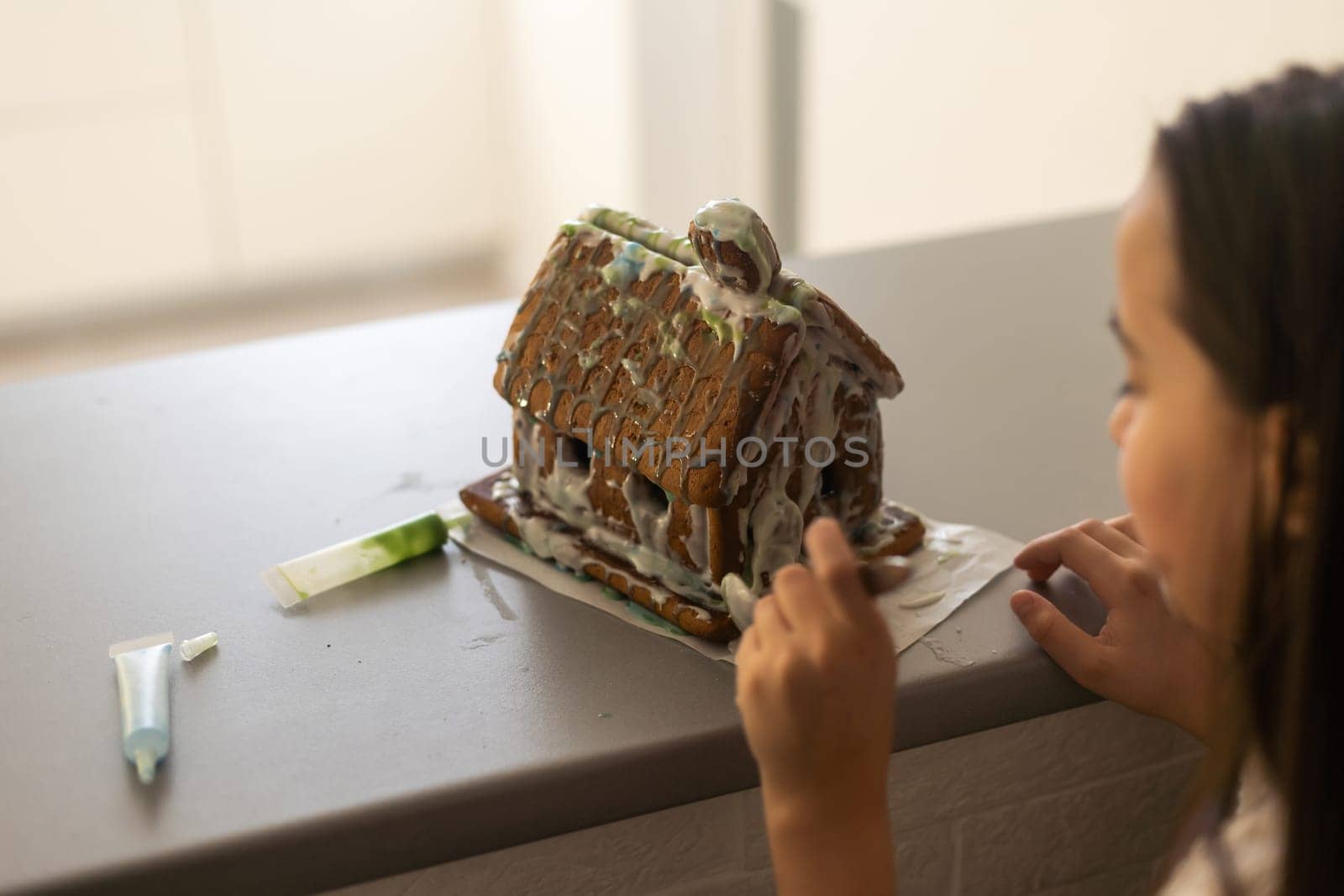 A girl plays with a gingerbread house for traditional Christmas decoration.
