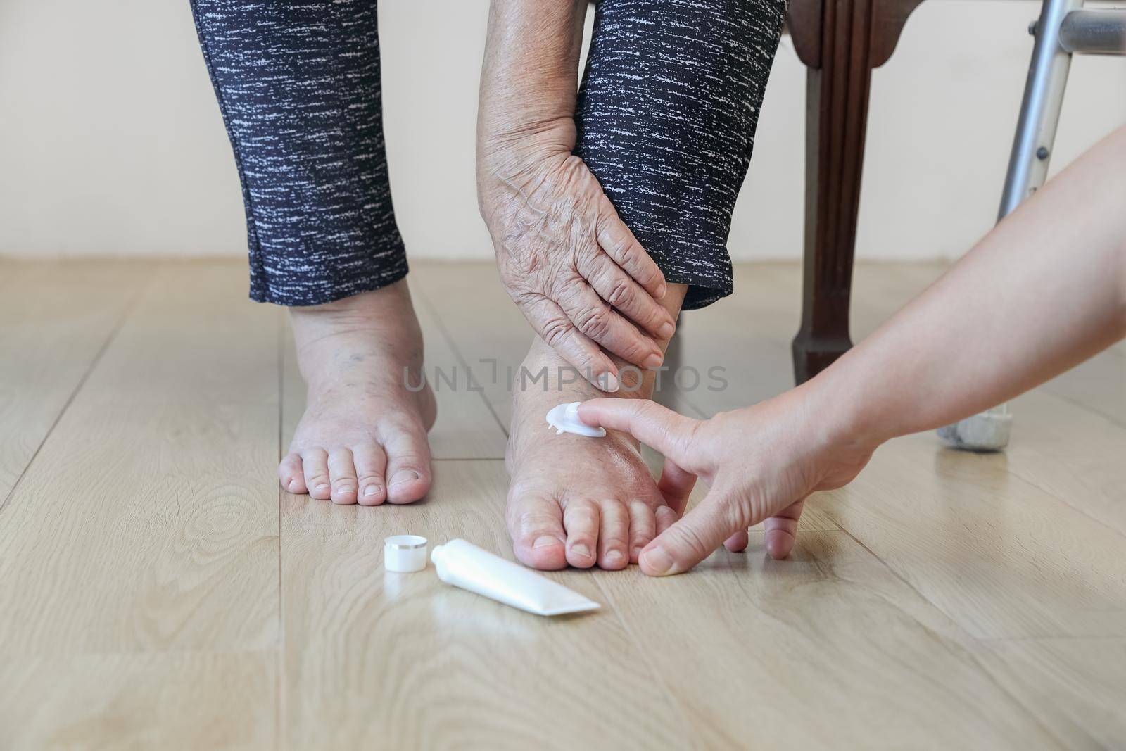 Elderly woman putting cream on swollen feet by toa55