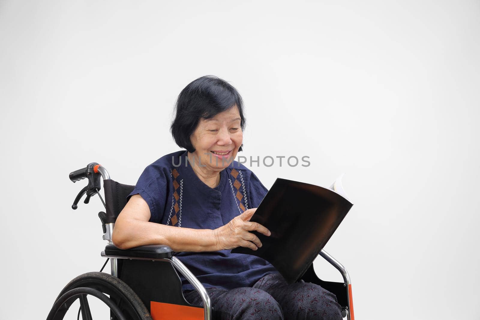 Senior asian woman smiling while reading magazine on white background. by toa55