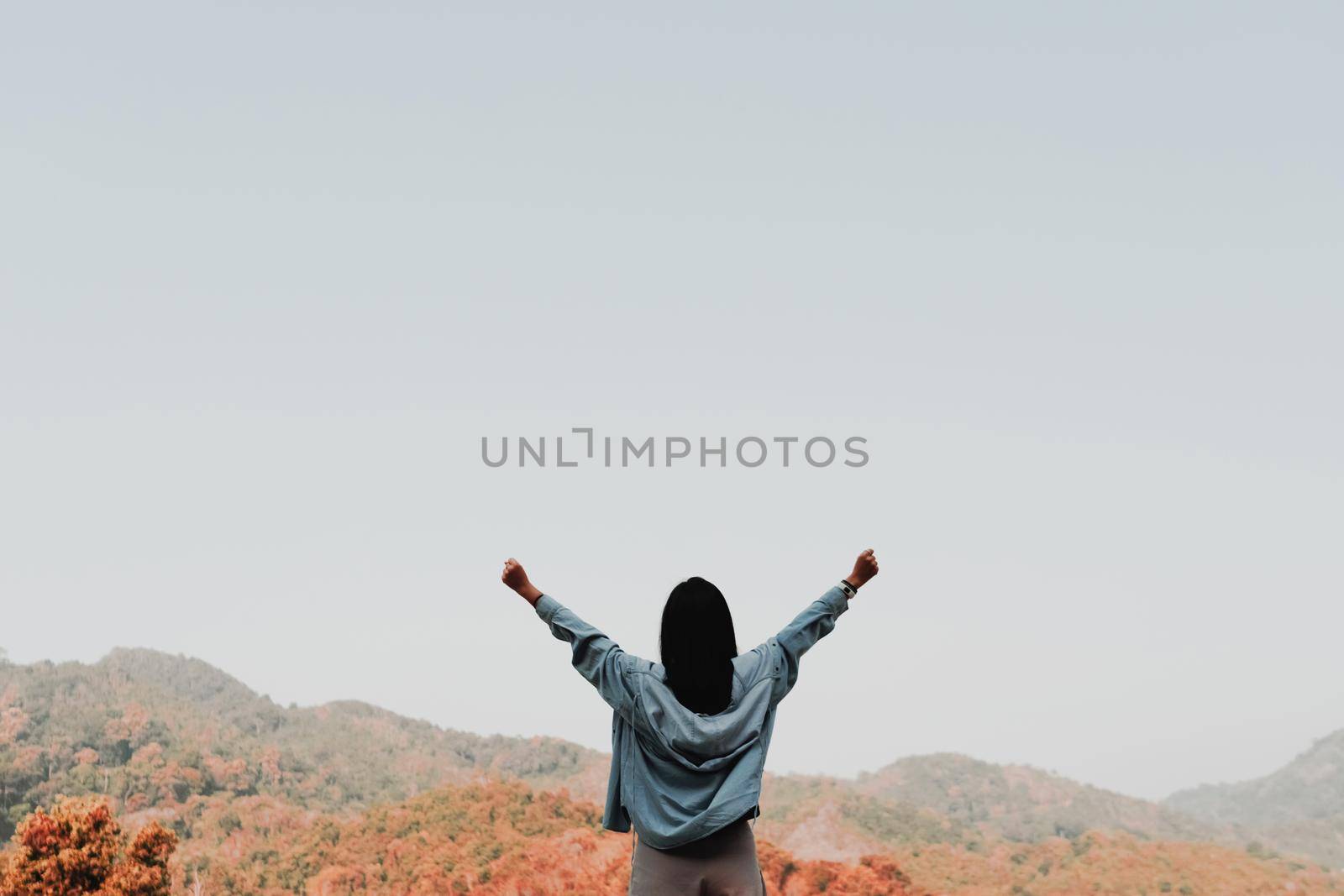 Woman rise hands up to sky freedom concept with blue sky and summer field mountain background.