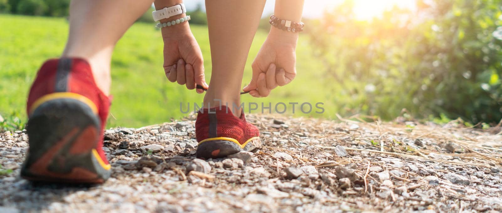 Woman wear running shoe on to walking and running on nature green background.Health exercise concept.
